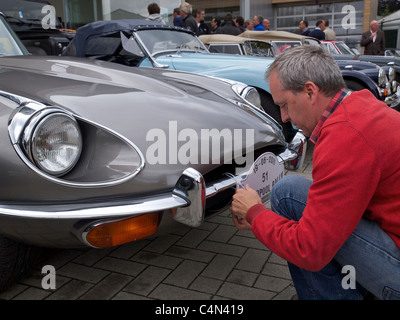 Jaguar E-type proprietario di attaccare un Rallye-segno per il paraurti anteriore, prima di partecipare a un classico auto rallye. Anversa in Belgio Foto Stock