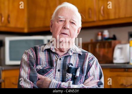 Un pensionato anziano Senior l uomo nella sua casa seduti su una sedia. Foto Stock