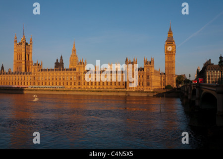 Westminster. Il Parlamento si illumina in early morning sun. Il fiume Tamigi giunchi da. Un blu chiaro mattina di primavera. Foto Stock