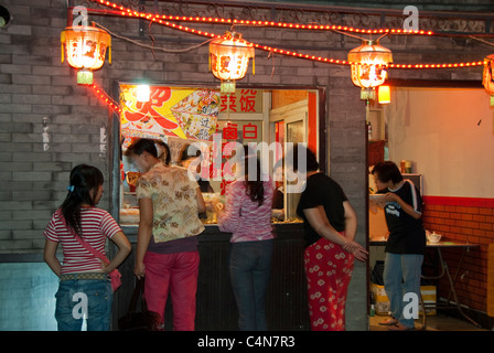 Pechino, Cina, gruppo di donne cinesi che ordinano cibo da asporto allo snack Bar sulla strada nel distretto del lago Houhai, di notte, luci vintage all'aperto, città vecchia cinese Foto Stock