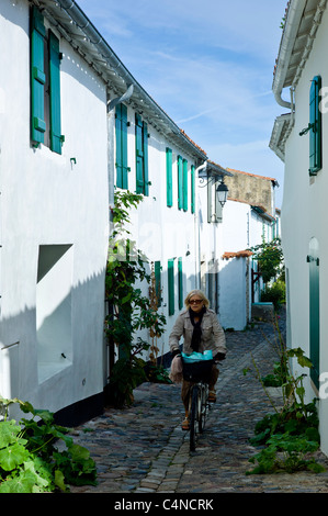 Tradizionale scena di strada cicli di donna lungo il vialetto di ciottoli a St Martin de Re, Ile de Re, Francia Foto Stock