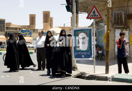 Donne iraniane in strada vicino a un manifesto di ayatollah Khomeini a Yazd, Iran Foto Stock