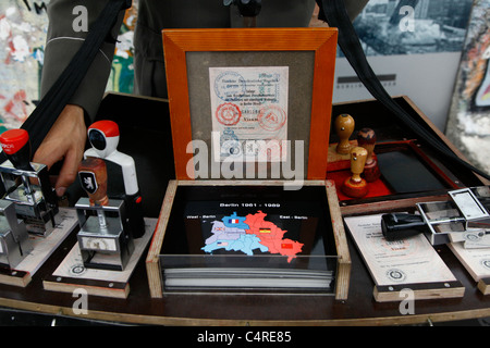 Un busker offre i francobolli passaporto della Germania orientale rilasciati ai cittadini dell'ex Repubblica democratica tedesca per i viaggi internazionali al Checkpoint charlie di Berlino, Germania Foto Stock