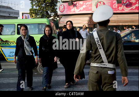 Donne iraniane che attraversano la strada a Rasht, Iran, con poliziotti che guardano il traffico Foto Stock