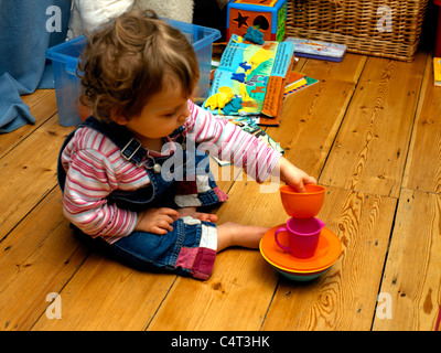 Diciotto mesi di età bambino edificio torre con bicchieri di plastica e ciotole Foto Stock