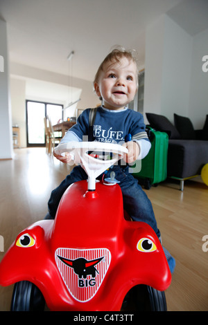 Little Boy, 1 anno di età è di esplorare la sua casa. Curiosamente esplorando l'appartamento. Su una macchina giocattolo, Bobby auto. Foto Stock