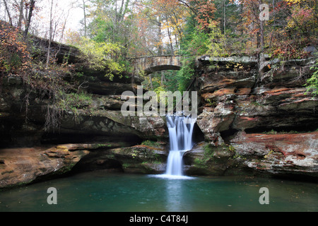 Una cascata e una pietra Ponte del piede nella panoramica Old Man's Cave del Parco Statale di Central Ohio in autunno, Hocking Hills Regione, STATI UNITI D'AMERICA Foto Stock