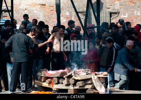 Cremazione indù in corso presso i ghat sulle rive del Bhagmati a Pashupatinath, il più sacro sito indù in Nepal Foto Stock