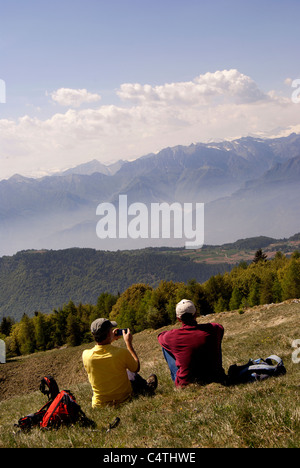 Un escursionista seduti sulla cima di una scogliera gode di vista panoramica Foto Stock