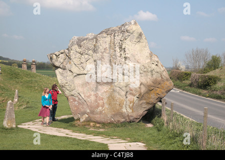 I visitatori a camminare accanto a un enorme cerchio esterno in pietra permanente, Avebury Henge & circoli di pietra sito, Wiltshire, Inghilterra. Foto Stock