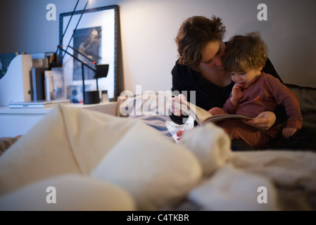 Azienda madre figlio toddler sul giro, lettura Bedtime Story nel letto Foto Stock