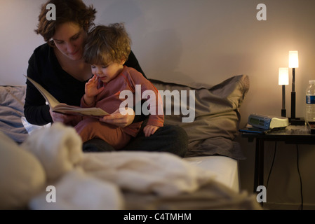 Azienda madre figlio toddler sul giro, lettura Bedtime Story nel letto Foto Stock