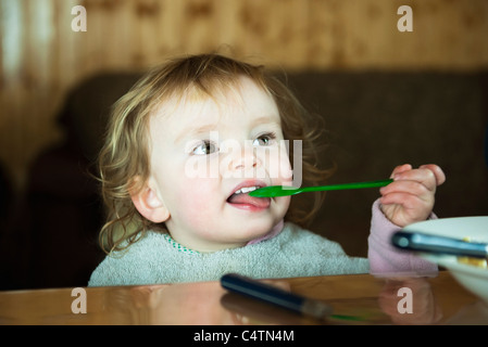 Il Toddler girl stessa alimentazione con cucchiaio Foto Stock