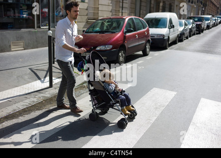 Padre spingendo il toddler figlio nel passeggino Foto Stock