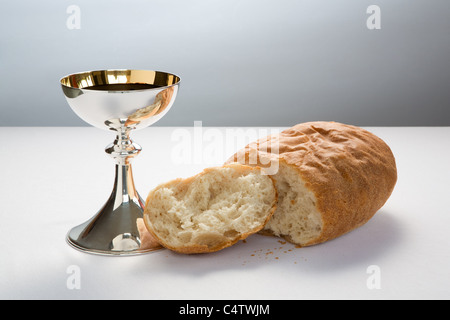 La santa Comunione cup (calice) con il vino e le rotture della pagnotta di pane, per la celebrazione del santo cristiano di comunione. Foto Stock