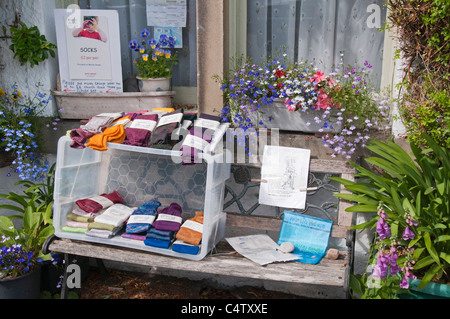 Scatola di calze fatte a mano in vendita al di fuori della casa privata, raccogliendo denaro per beneficenza (volantini che promuovono raccolta fondi) - Grassington, Yorkshire, Inghilterra, UK. Foto Stock