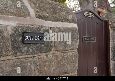 Porta d'ingresso a casa (cancello e muro di pietra) e segnali di avvertimento (24 ore CCTV e attenzione al cane). Misure di sicurezza e prevenzione della criminalità - Yorkshire, Inghilterra, UK. Foto Stock