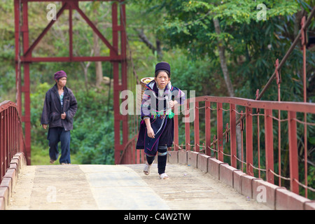 Nero H'mongs minoranza etnica donna cammina attraverso ponte di Sapa, Vietnam Foto Stock