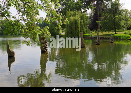 Contemporary Sculpture Garden a Burghley House. La scultura moderna di cinque sculture in legno nel lago in un giardino paesaggistico. Foto Stock