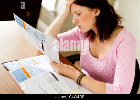 Donna che guarda le bollette delle utenze Foto Stock