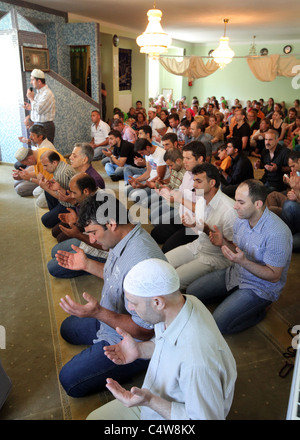 Musulmani turchi (anteriore) guardato da cristiani tedeschi (retro) durante una preghiera del venerdì nella moschea di Dresda, in Germania. Foto Stock