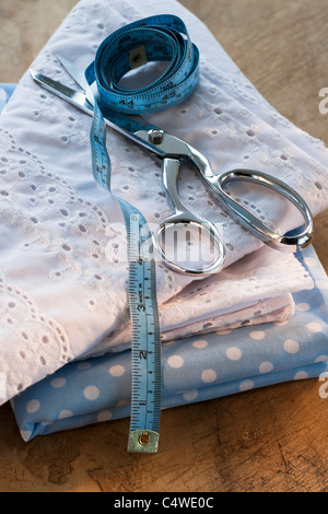 Close-up di prodotti tessili ripiegata con forbici e nastro di misurazione Foto Stock