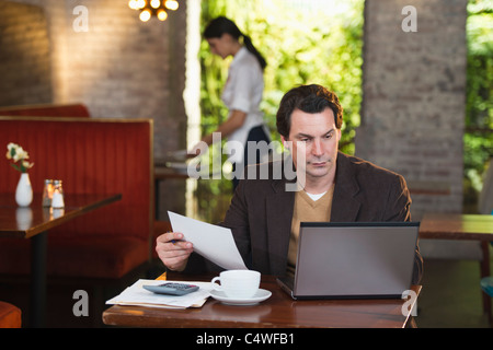 Stati Uniti d'America, New York New York City, proprietario lavora con il computer portatile nel ristorante con cameriera in background Foto Stock