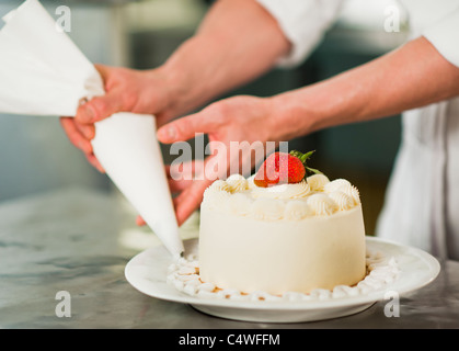 Stati Uniti d'America, nello Stato di New York, New York City, chef pasticcere decorare la torta Foto Stock