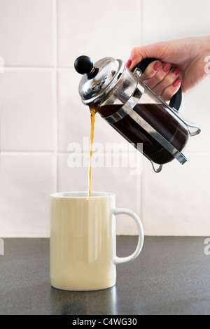 Giovani caucasici mano womans versando il caffè nella tazza da cafetiere presi in Bristol, Regno Unito Foto Stock