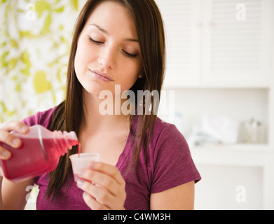 Stati Uniti d'America, New Jersey, Jersey City, giovane donna colata di sciroppo nella coppa di misurazione Foto Stock