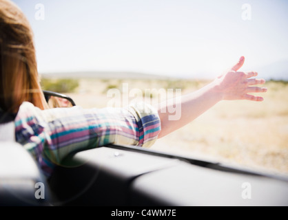 Stati Uniti, California, Palm Springs, Coachella Valley, San Gorgonio Pass, Donna braccio di estensione al di fuori di autovettura convertibile Foto Stock