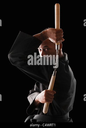 Studio shot dell'uomo esercitando con nunchaku Foto Stock