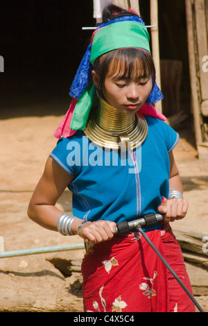 Un Karen Paduang donna che indossa gli anelli in oro intorno al suo collo è utilizzando una pompa ad acqua a casa sua in un campo di rifugiati in Thailandia. Foto Stock