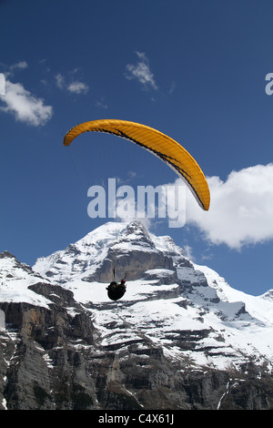 Parapendio prendendo per i cieli sopra Gimmelwald, con Jungfrau in background Foto Stock