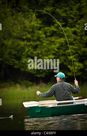 Un uomo tira in una trota pescata la pesca sulle sponde di un lago in Boulder Junction, Wisconsin. Foto Stock