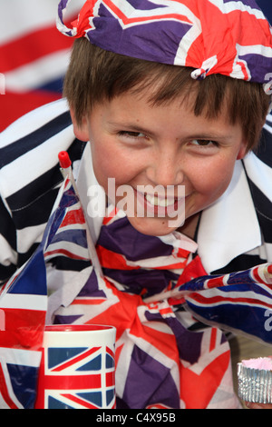 Close up ritratto di un giovane ragazzo che sorride pur avendo una tazza di tè e adornata con Union Jack Flag. Foto Stock