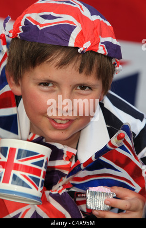 Close up ritratto di un giovane ragazzo che sorride pur avendo una tazza di tè e adornata con Union Jack Flag. Foto Stock