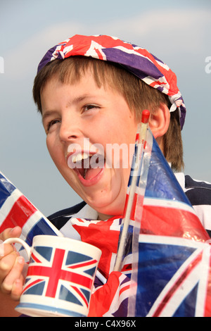 Close up ritratto di un giovane ragazzo di ridere mentre avente una tazza di tè, adornata con Union Jack Flag. Foto Stock