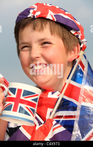 Close up ritratto di un giovane ragazzo di ridere mentre avente una tazza di tè, adornata con Union Jack Flag. Foto Stock