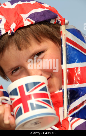 Close up ritratto di un giovane ragazzo che sorride mentre avente una tazza di tè, adornata con Union Jack Flag. Foto Stock