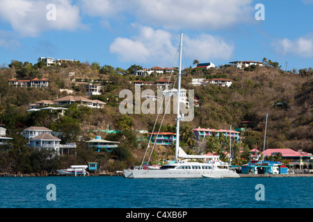 Barca a vela di lusso attraccata a Leverick Bay con case in collina su Virgin Gorda in Isole Vergini Britanniche Foto Stock