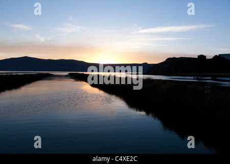 Un canale in entrata per le isole galleggianti di Uros sul lago Titicaca nelle Ande peruviane. È il tramonto. Foto Stock