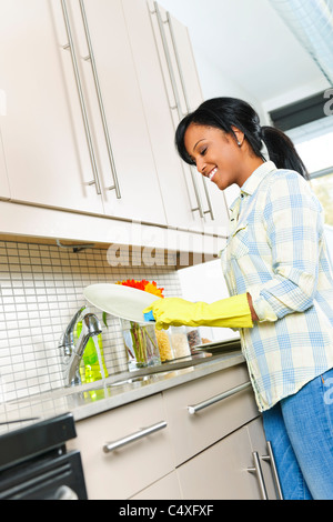 Sorridente giovane donna nero lavaggio piatti in cucina Foto Stock