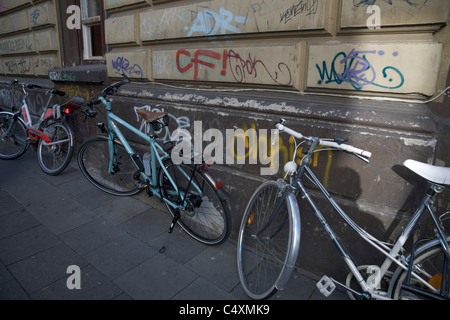 Biciclette appoggiata contro un muro coperto di graffiti Colonia Germania Foto Stock