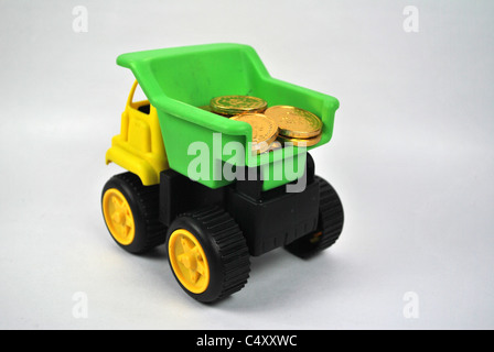 Toy giocoso autocarro autocarro auto mobile wealth denaro moneta in oro silo tagliare cut-out retro bianco terreno isolato giallo verde nero Foto Stock