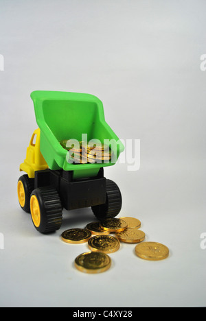 Toy giocoso autocarro autocarro auto mobile wealth denaro moneta in oro silo tagliare cut-out retro bianco terreno isolato giallo verde nero Foto Stock