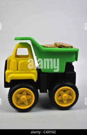 Toy giocoso autocarro autocarro auto mobile wealth denaro moneta in oro silo tagliare cut-out retro bianco terreno isolato giallo verde nero Foto Stock