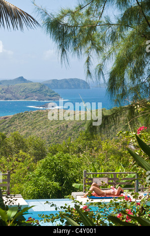 Donne in bikini prendere il sole a bordo piscina presso il resort di montagna a Bequia, St. Vincent e Grenadine. Foto Stock