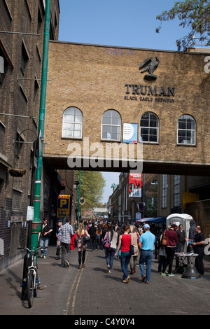 People shopping in strada dei mercati al di fuori del Vecchio Truman Brewery in Brick Lane, London, England, Regno Unito Foto Stock