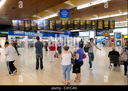 Passeggeri controllando la data di arrivo e di partenza le schede informazioni sull'area atrio di Leeds stazione ferroviaria, Inghilterra. Foto Stock